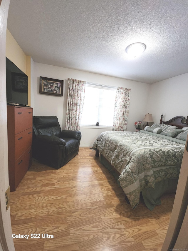 bedroom with a textured ceiling and light hardwood / wood-style floors