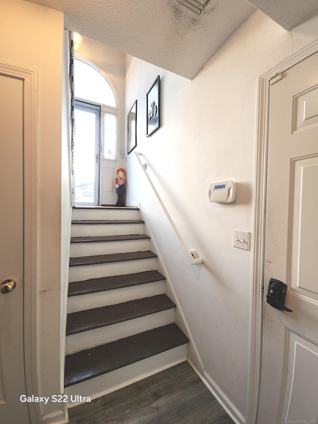 stairway featuring wood-type flooring and a textured ceiling