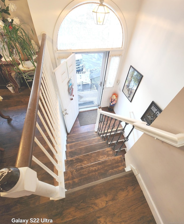 stairs with hardwood / wood-style floors and a high ceiling