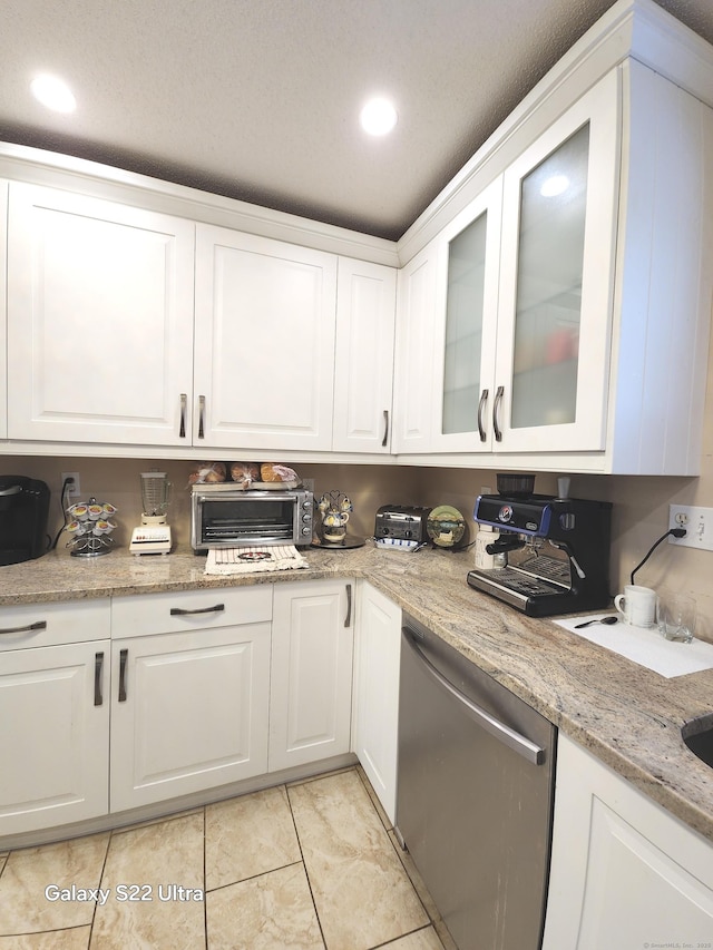 kitchen featuring white cabinetry, light tile patterned floors, stainless steel dishwasher, and light stone countertops