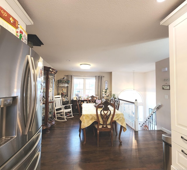 dining room with dark wood-type flooring and a textured ceiling