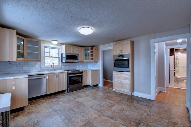 kitchen with light brown cabinetry, sink, decorative backsplash, and appliances with stainless steel finishes