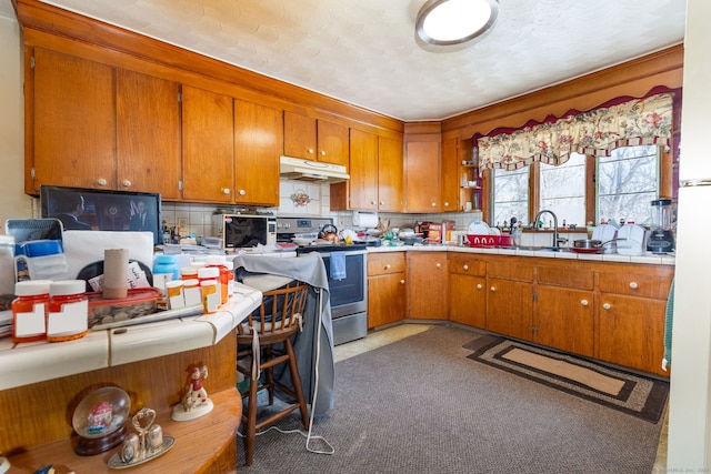 108 Fall Mountain Rd, Bristol, CT 06010 - kitchen featuring stainless steel electric stove, under cabinet range hood, brown cabinetry, tile countertops, and decorative backsplash