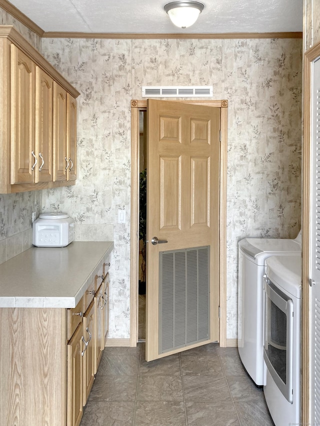 laundry area featuring cabinets, ornamental molding, dark tile patterned flooring, and washing machine and dryer