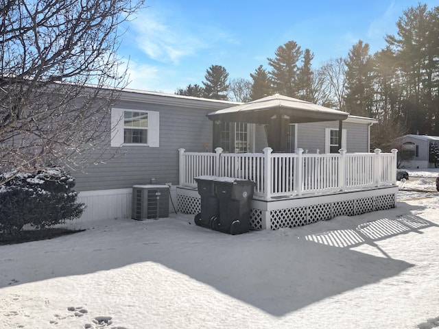 snow covered house with central AC and a deck