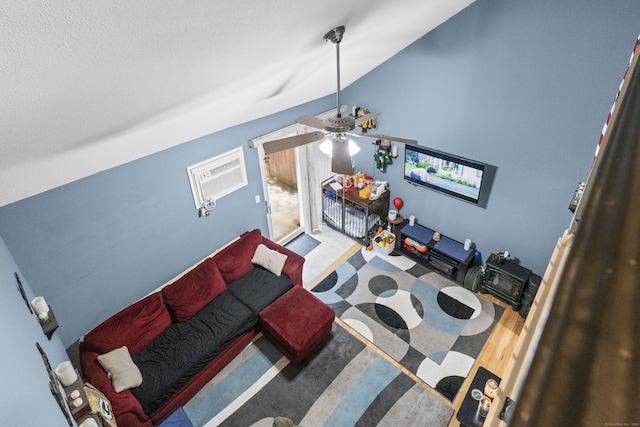 living room with ceiling fan, vaulted ceiling, and a wall mounted AC