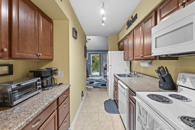 kitchen featuring sink, light stone counters, light tile patterned floors, track lighting, and white appliances