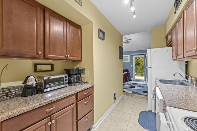 kitchen featuring light tile patterned floors, sink, range, light stone counters, and white dishwasher