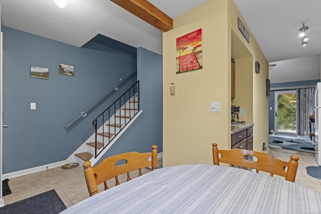 tiled dining space featuring beam ceiling