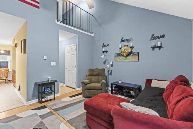 living room featuring hardwood / wood-style floors, ceiling fan, and a high ceiling