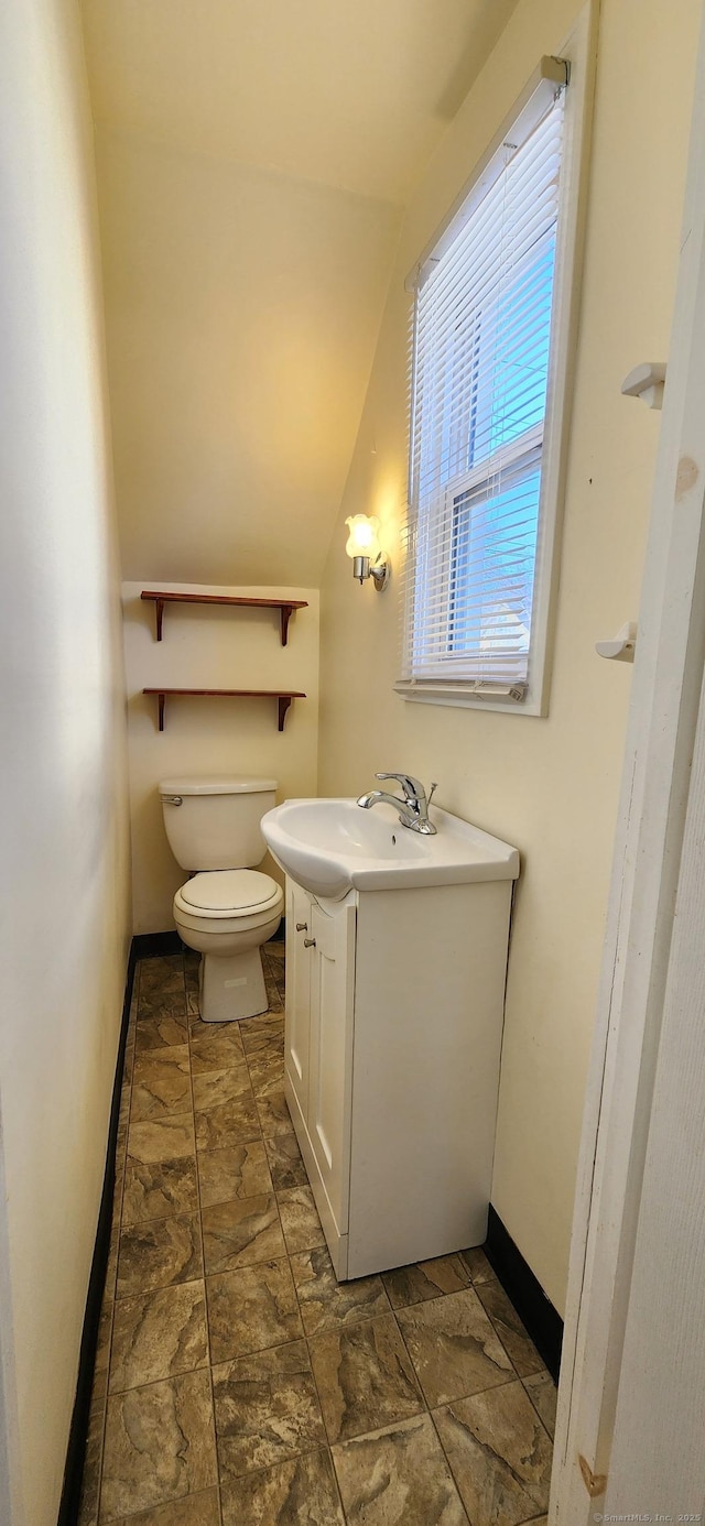 bathroom featuring lofted ceiling, vanity, and toilet