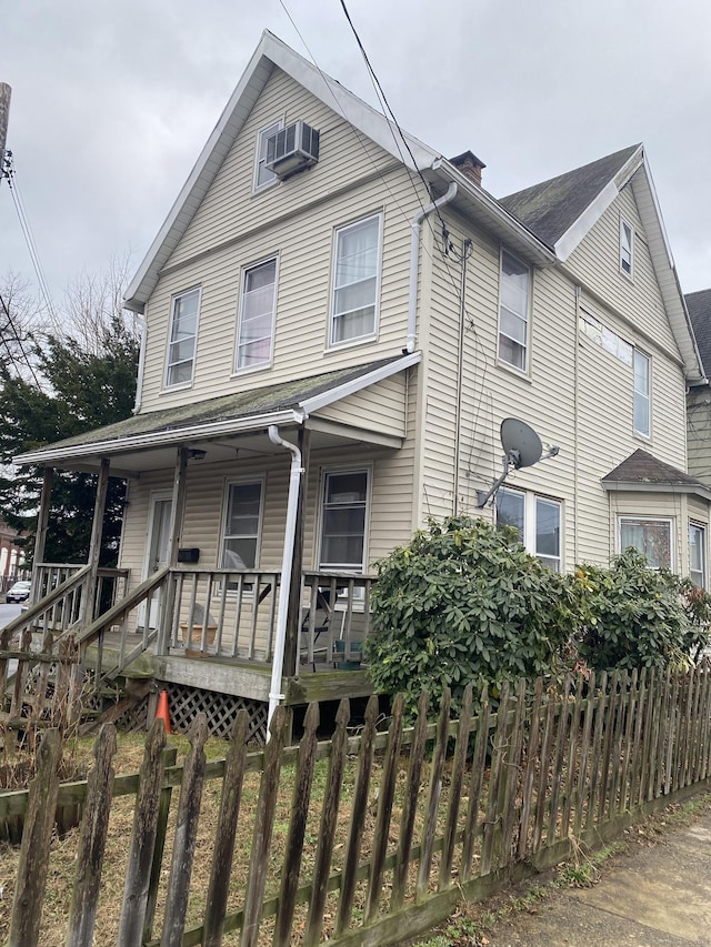 view of front of home with covered porch, fence, and a chimney