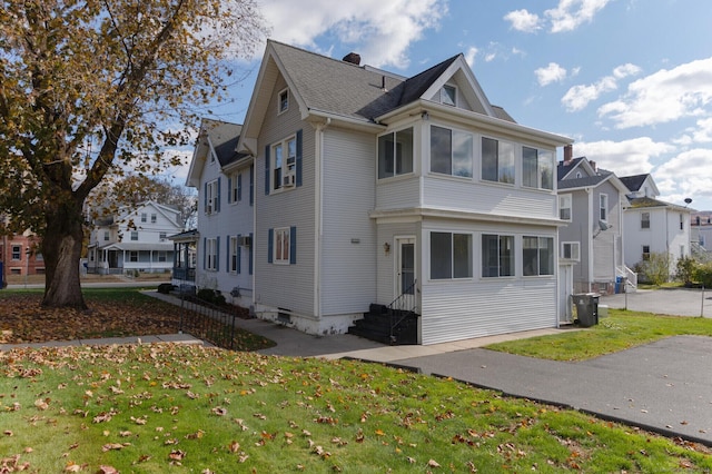 view of side of home with a sunroom and a yard