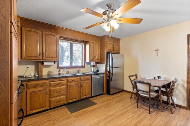 kitchen featuring ceiling fan, stainless steel appliances, sink, and light hardwood / wood-style floors