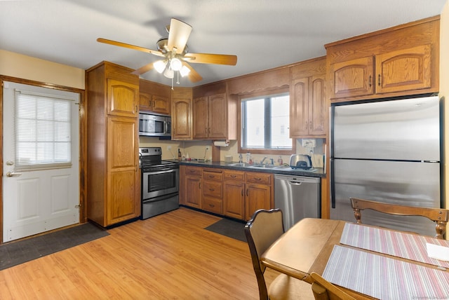 kitchen with ceiling fan, appliances with stainless steel finishes, sink, and light hardwood / wood-style floors