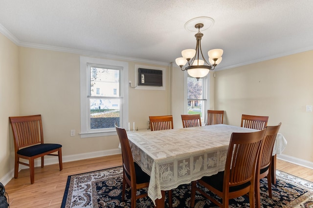 dining room featuring an inviting chandelier, ornamental molding, light hardwood / wood-style floors, and an AC wall unit