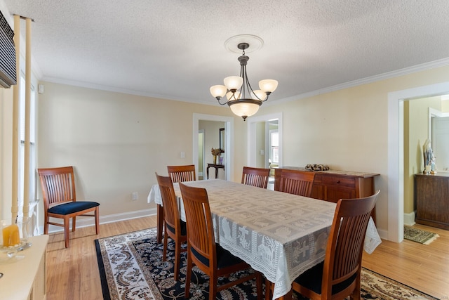 dining area featuring an inviting chandelier, ornamental molding, light hardwood / wood-style floors, and a textured ceiling