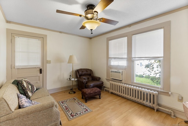 living area featuring crown molding, ceiling fan, radiator heating unit, and light wood-type flooring