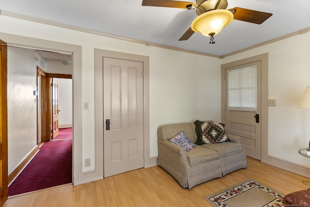 living area with crown molding, ceiling fan, and light wood-type flooring