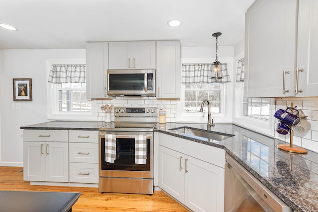 kitchen with a wealth of natural light, decorative backsplash, stainless steel appliances, and a sink