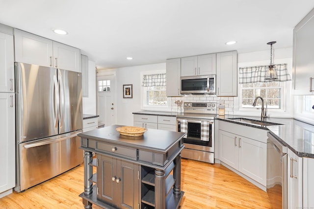 kitchen featuring sink, a center island, hanging light fixtures, stainless steel appliances, and decorative backsplash