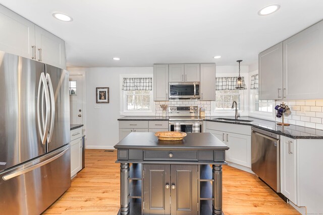 kitchen featuring sink, appliances with stainless steel finishes, a kitchen island, pendant lighting, and a healthy amount of sunlight