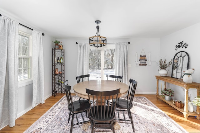 dining space with a notable chandelier, light wood-style floors, and baseboards