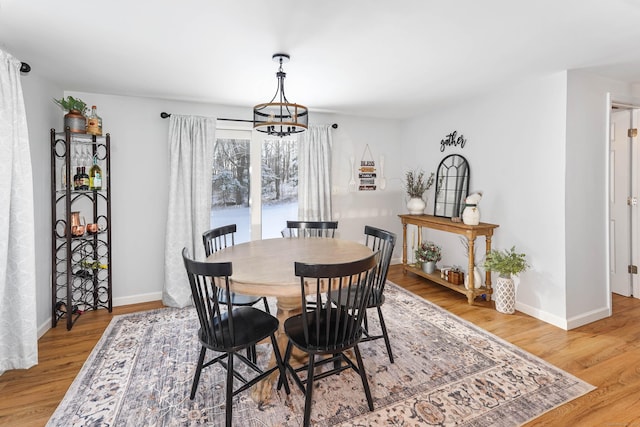 dining area featuring baseboards, an inviting chandelier, and light wood finished floors