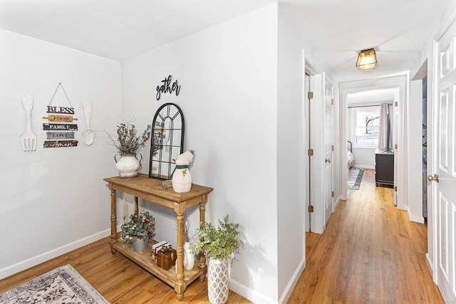 hall with light wood-style flooring and baseboards