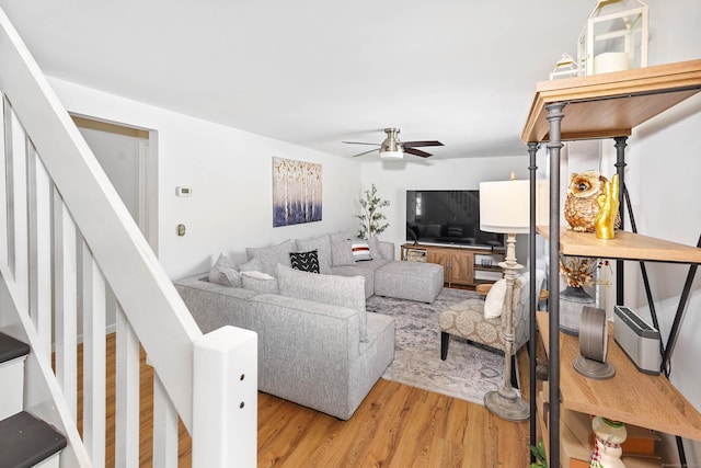 living area featuring a ceiling fan, stairway, and light wood-style floors