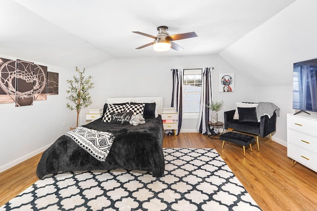 bedroom with light wood finished floors, baseboards, and vaulted ceiling