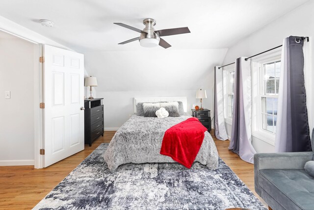 bedroom with baseboards, light wood-style floors, a ceiling fan, and vaulted ceiling