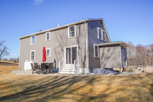 back of house featuring entry steps, a patio, and a lawn