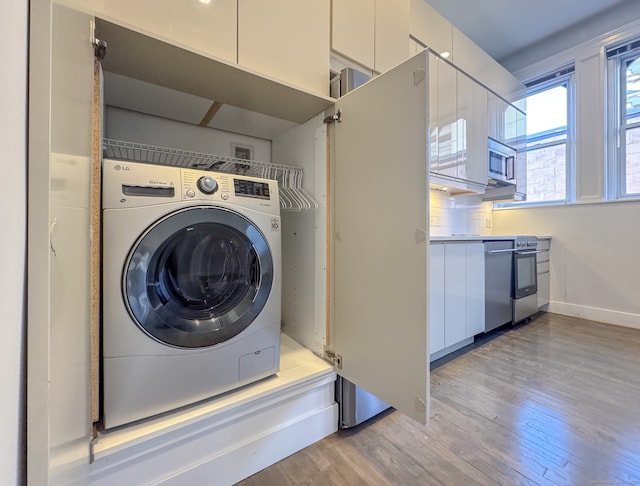 clothes washing area with washer / clothes dryer and light hardwood / wood-style floors