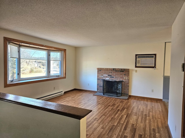 unfurnished living room with wood-type flooring, baseboard heating, a brick fireplace, a textured ceiling, and a wall unit AC