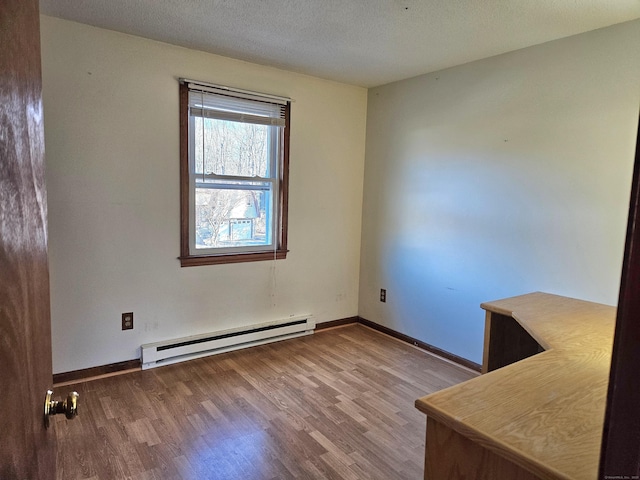 unfurnished room with hardwood / wood-style flooring, a baseboard radiator, and a textured ceiling