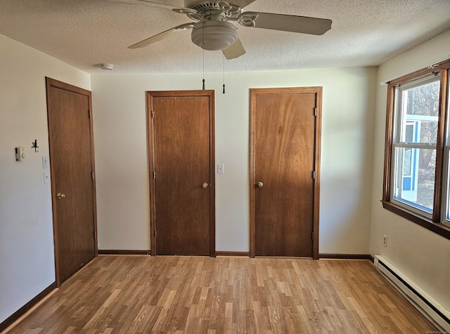 unfurnished bedroom with light hardwood / wood-style floors, a textured ceiling, and baseboard heating