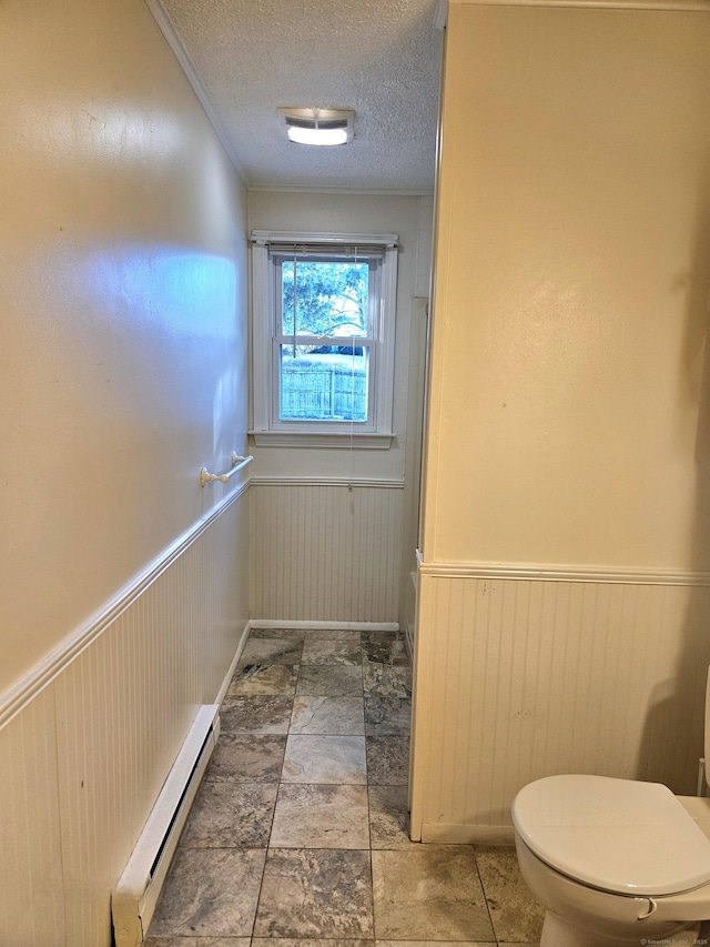 bathroom with toilet, a textured ceiling, and baseboard heating