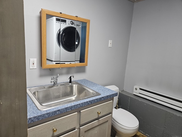 bathroom with baseboard heating, stacked washer / dryer, vanity, and toilet