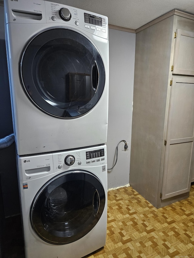 laundry area with a textured ceiling, light parquet flooring, and stacked washer / dryer