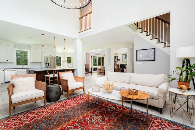 living room featuring a notable chandelier, sink, and ornate columns