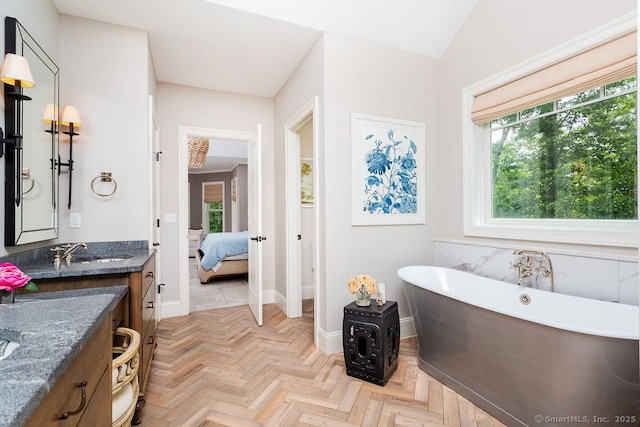 bathroom featuring vanity, parquet floors, and a tub