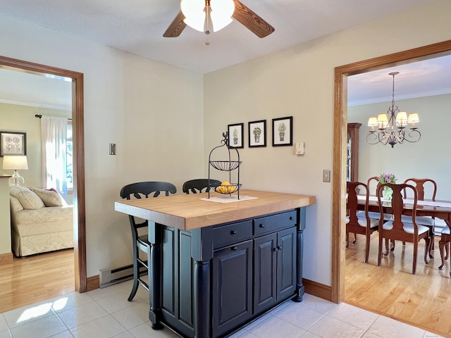 kitchen featuring butcher block counters, hanging light fixtures, light tile patterned floors, and crown molding