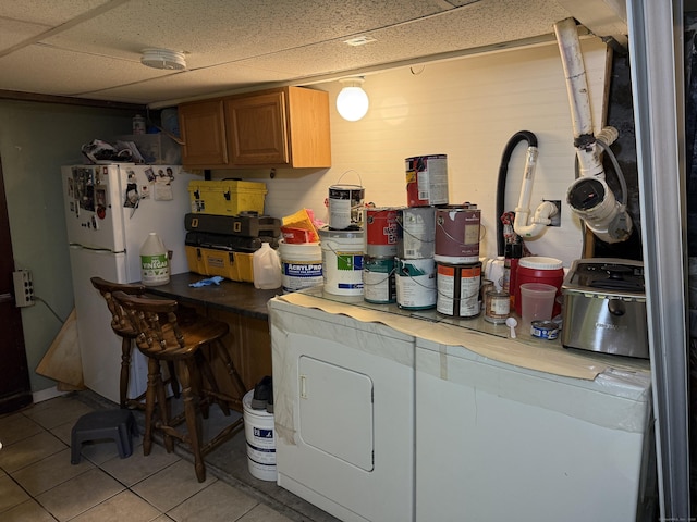 kitchen featuring a drop ceiling, light tile patterned floors, and white fridge