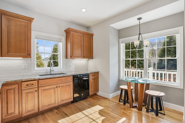 kitchen with sink, light stone counters, black dishwasher, pendant lighting, and backsplash