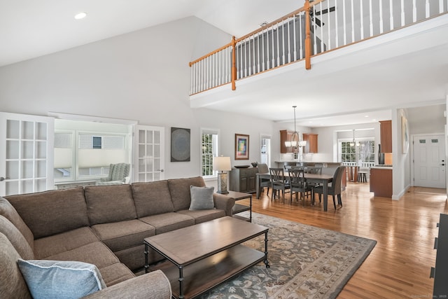 living room with high vaulted ceiling, a chandelier, and light hardwood / wood-style flooring