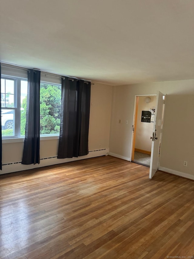 empty room featuring light wood-type flooring and baseboard heating