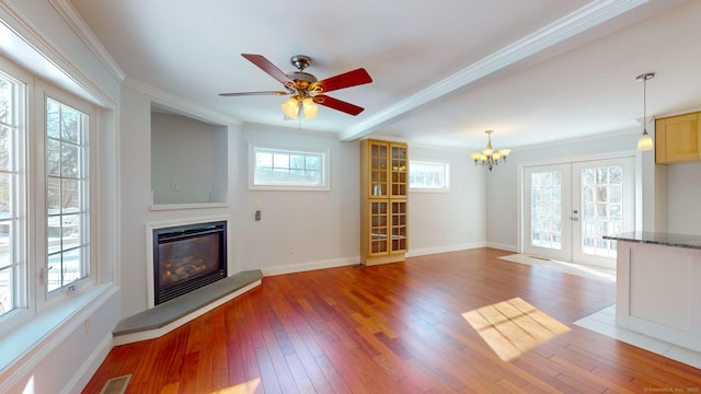 unfurnished living room featuring crown molding, light hardwood / wood-style flooring, french doors, and ceiling fan with notable chandelier