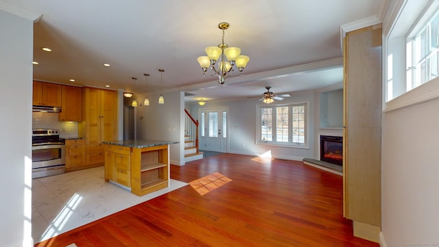 kitchen with backsplash, electric range, a kitchen island, decorative light fixtures, and light wood-type flooring