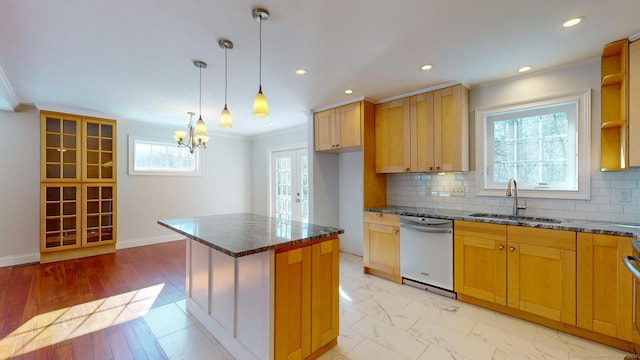 kitchen featuring sink, crown molding, dark stone countertops, stainless steel dishwasher, and a kitchen island